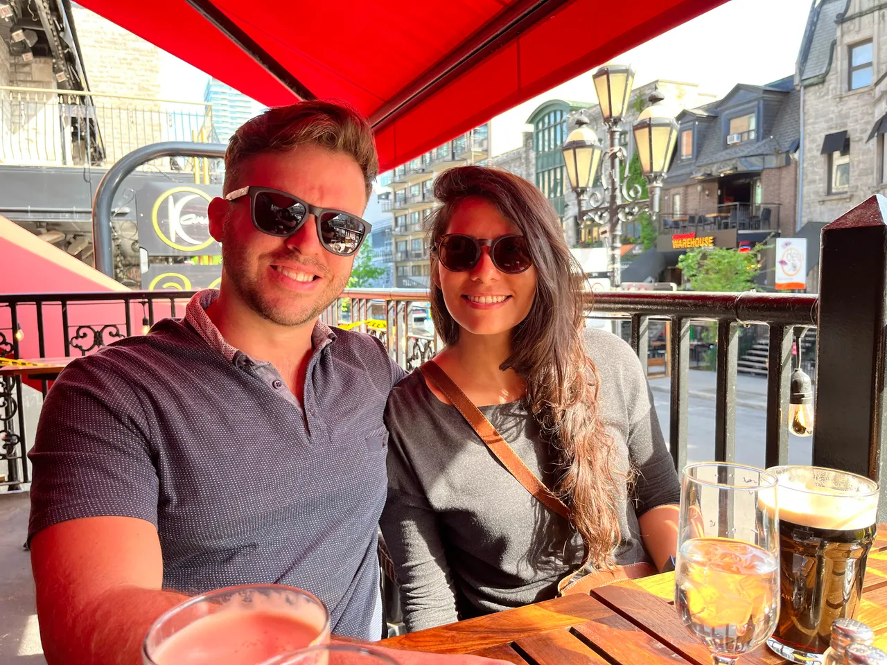 Patrick and his wife at an outdoor cafe table under a red awning in Montreal